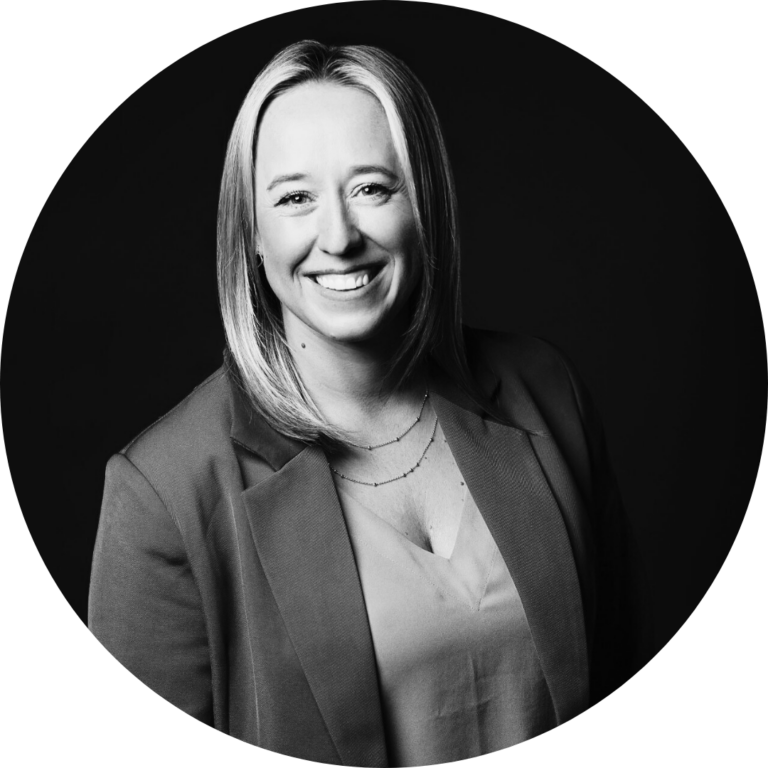Business Aviation Group Black and white portrait of a smiling woman with straight, shoulder-length hair, wearing a blazer and blouse, set against a dark circular background—an inspiring representation of our talented team members.