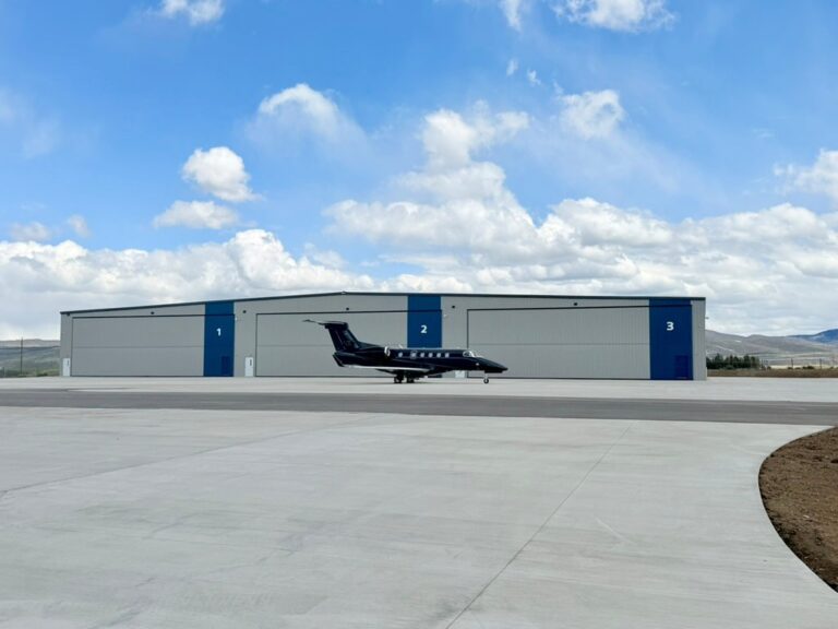 Business Aviation Group A small private jet is parked on the tarmac in front of three large hangars labeled 1, 2, and 3 under a partly cloudy sky.