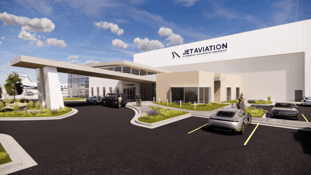 Business Aviation Group Modern airport terminal building with "Jet Aviation" sign at the Rocky Mountain Metropolitan Airport, parked cars, and people walking outside under a partly cloudy sky.